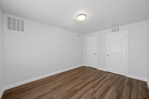 A room with wooden flooring and two white doors.