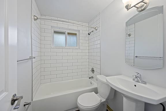 A white bathroom with a tub, toilet, and sink.