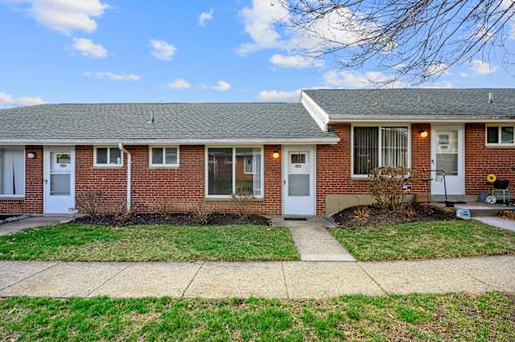A red brick house with a white door and a small front yard.