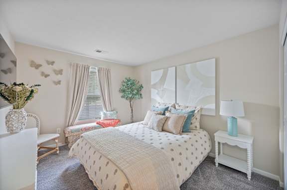 A bedroom with a large bed and a white chair.
