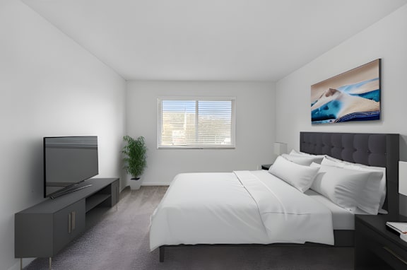 A bedroom with a bed, a television, and a painting on the wall.