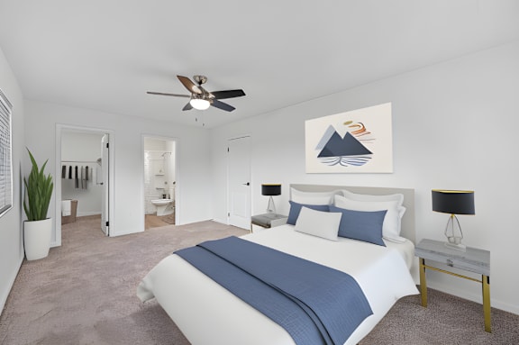 A bedroom with a large bed and a ceiling fan.