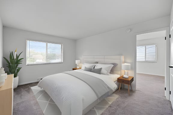 A bedroom with a large bed and a potted plant.
