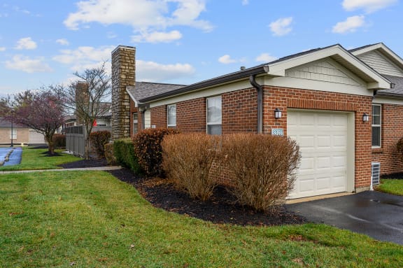 Brick house with a white garage door and a lawn at Four Bridges, Ohio