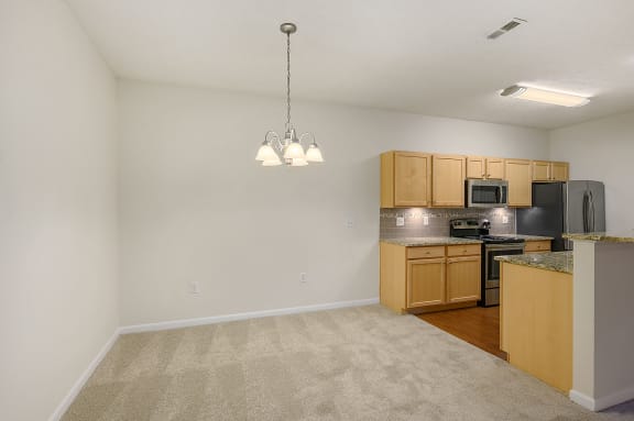 Empty living room with a kitchen with a stove and a refrigerator at Four Bridges, Liberty Township