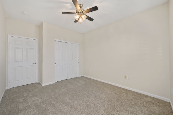 Empty living room with a ceiling fan and two doors at Four Bridges, Ohio
