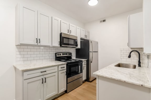 a kitchen with white cabinets and stainless steel appliances