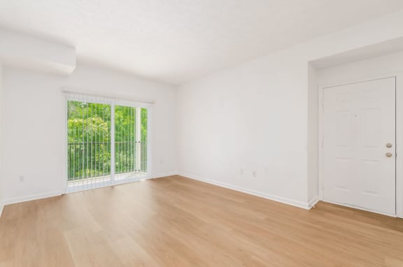 an empty living room with wood floors and a window