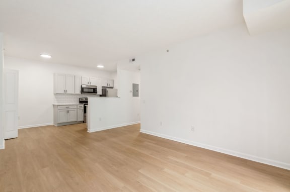 an empty living room and kitchen with white walls and wood floors