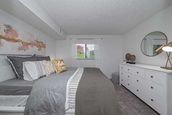 A bedroom with a bed, dresser, and mirror.