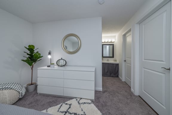 a white bedroom with a white dresser and a mirror
