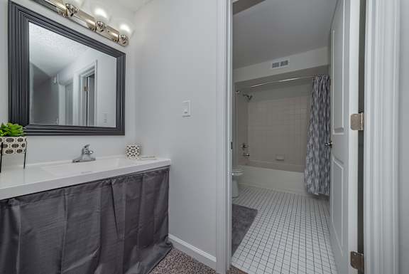 A bathroom with a black mirror and a white sink.