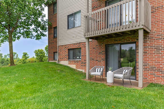A balcony with chairs and a table is on the side of a brick building.