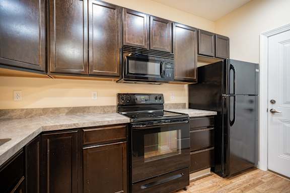 A kitchen with dark wood cabinets and black appliances.