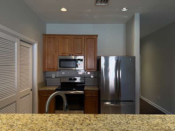 A kitchen with a refrigerator, microwave, and stove.