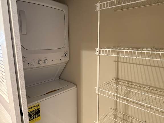 A white dishwasher is next to an empty wire shelf.