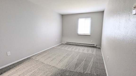 A room with a carpeted floor and a window.