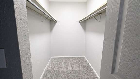 A hallway with a carpet and two shelves on the wall.