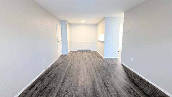 A room with wooden flooring and white walls.