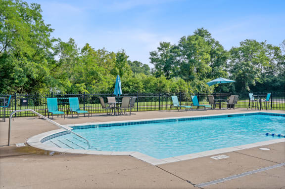 Swimming pool with blue chairs and umbrellas and a black fence around it at Galbraith Pointe Apartments and Townhomes, Cincinnati, OH, 45231