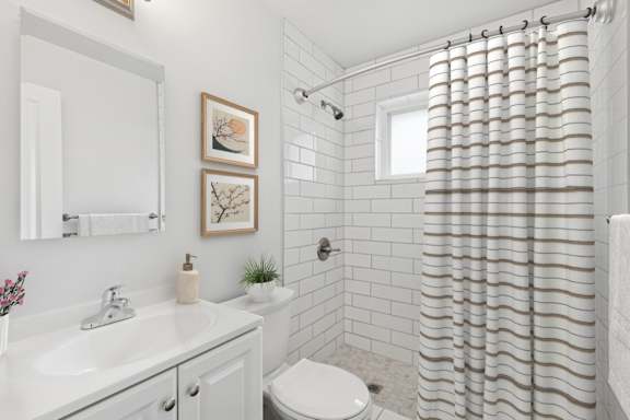 A white bathroom with a shower curtain and a toilet.