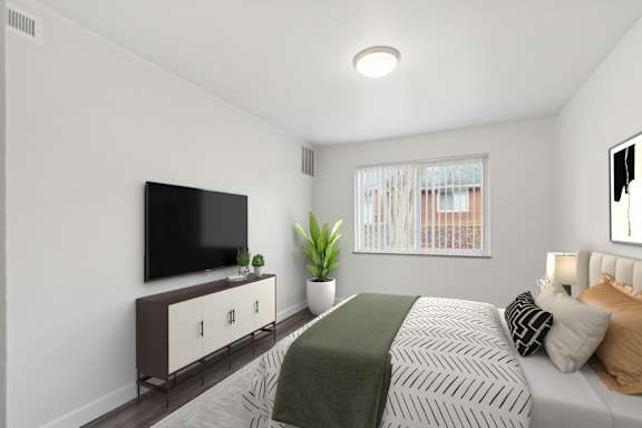 A bedroom with a bed, a television, and a plant.