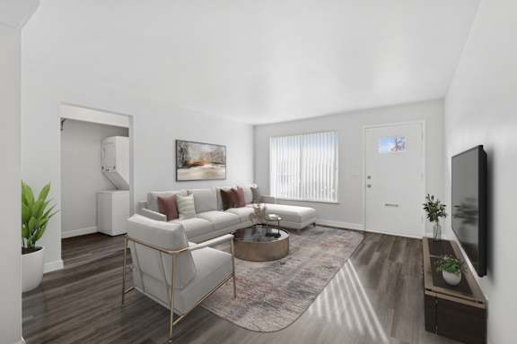 A living room with a white couch, a coffee table, and a television.