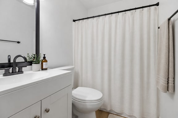 A white bathroom with a toilet, sink, and shower curtain.