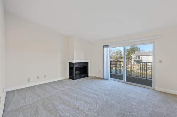 an empty living room with a fireplace and a patio door at Harpers Point Apartments, Ohio