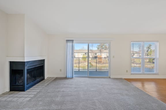 a living room with a fireplace and a door to a balcony at Harpers Point Apartments, Cincinnati