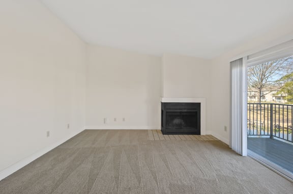 an empty living room with a fireplace and a balcony at Harpers Point Apartments, Ohio