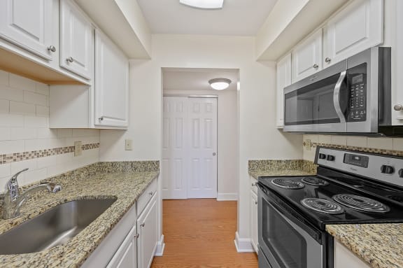 a kitchen with white cabinets and black appliances and granite counter tops at Harpers Point Apartments, Cincinnati,OH, 45249