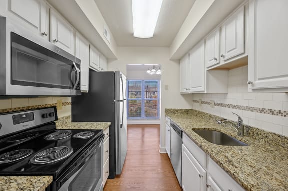 a kitchen with white cabinets and granite counter tops at Harpers Point Apartments, Cincinnati