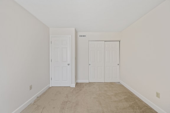 a bedroom with two doors and a carpeted floor at Harpers Point Apartments, Cincinnati,OH, 45249
