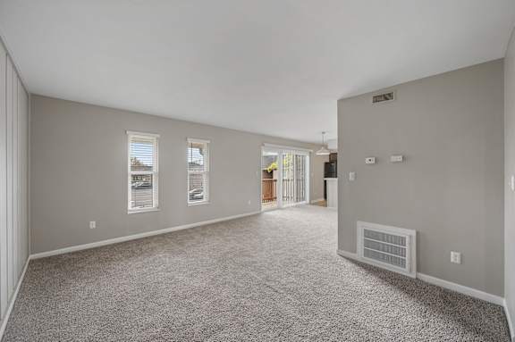 A spacious room with carpeted floor and a door at the end.