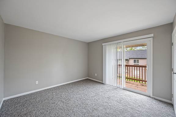 A room with a carpeted floor and a sliding glass door leading to a deck.