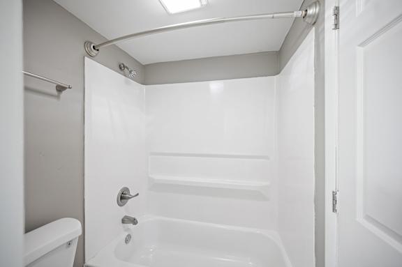A white bathroom with a tub, toilet and shower.