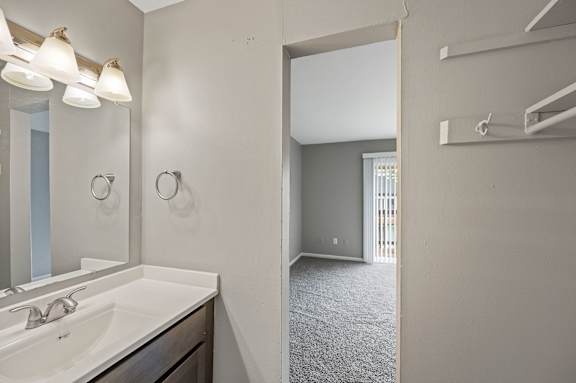 A bathroom with a sink, mirror, and light fixture.