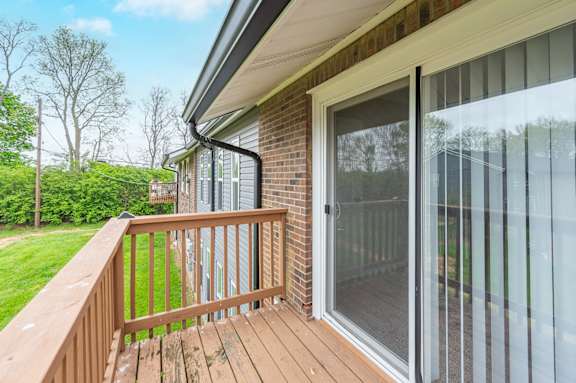 A wooden deck with a glass door leading to a patio.