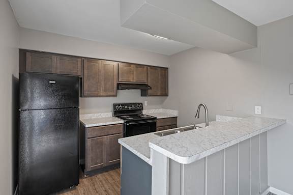 A kitchen with a black fridge and a white counter top.