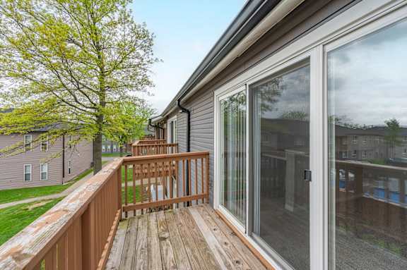 A wooden deck with a railing and sliding glass doors.