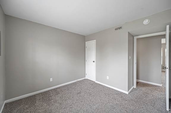 A room with a carpeted floor and two doors.