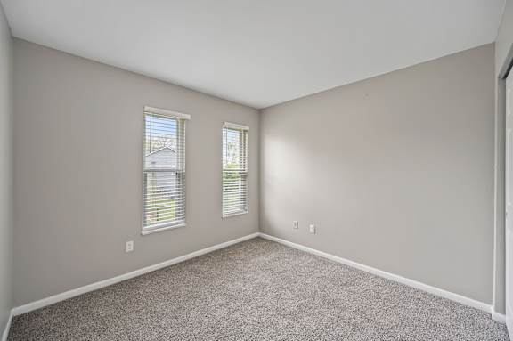 A room with two windows and carpeted floor.