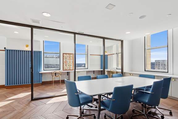 A conference room with a long table and blue chairs.