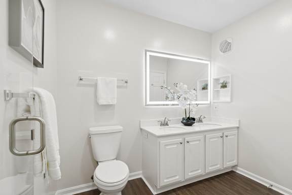 A white bathroom with a toilet, sink, and mirror. at Roebling Row, Covington, 41011-1720