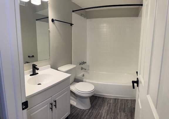 A white bathroom with a toilet, sink, and bathtub at Quail Run Apartments, ColumbusA white bathroom with a toilet, sink, and bathtub