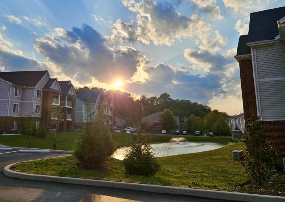 a sunset over a pond in a neighborhood with houses