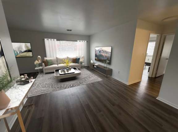 A modern living room with a dark wood floor and a large window with white curtains.