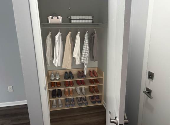 A white closet with clothes and shoes.