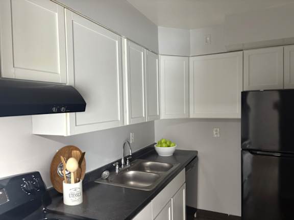 A kitchen with black appliances and white cabinets.